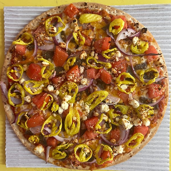 Casa Di Pizza's whole pizza with red tomatoes, yellow peppers, red onions, and feta cheese.
