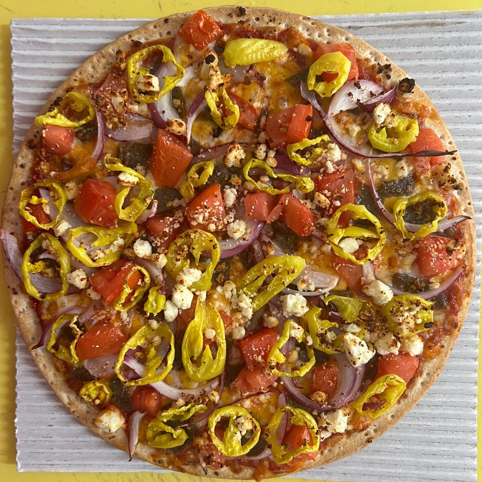 Casa Di Pizza's whole pizza with red tomatoes, yellow peppers, red onions, and feta cheese.