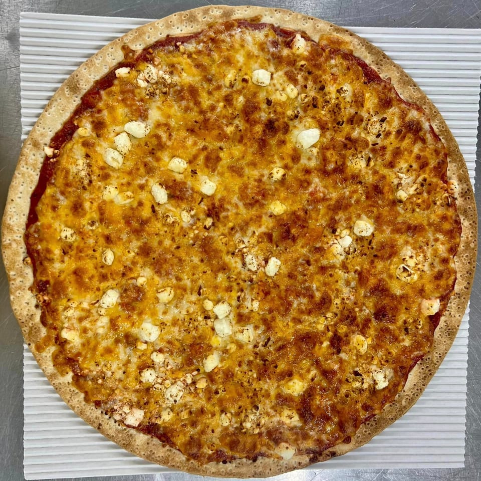 A whole Casa Di Pizza cheese pizza with a golden crust and melted cheese, topped with feta.
