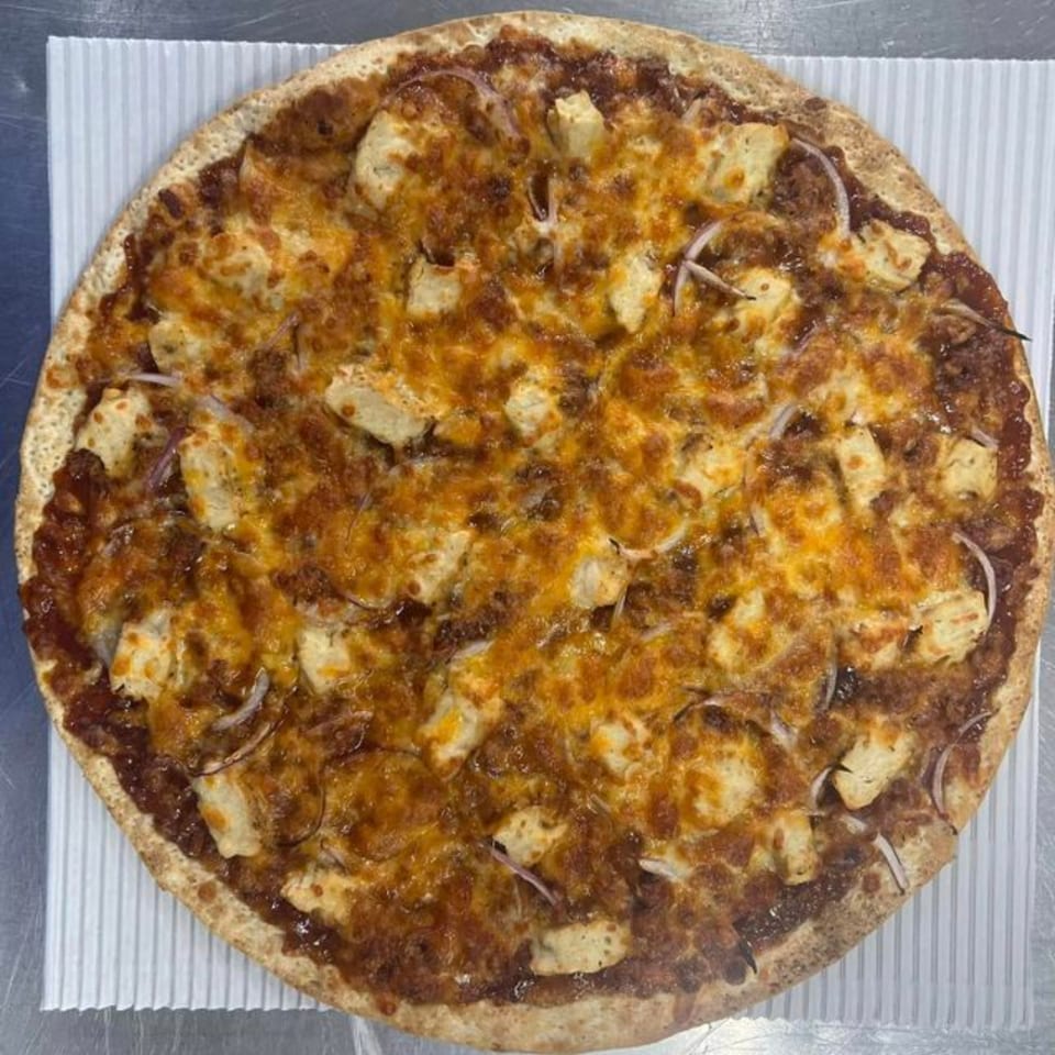A Casa Di Pizza BBQ chicken pizza, topped with melted cheese, chicken pieces, and red onion.