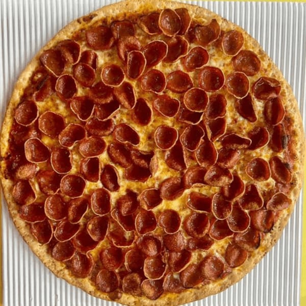 A whole, round Casa Di Pizza pepperoni pizza with a golden crust on a striped surface.