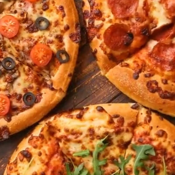 Three Casa Di Pizza pizzas with various toppings, including pepperoni, olives, and tomatoes.